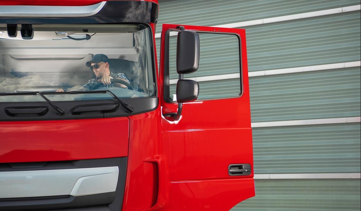 kierowca w czerwonej ciężarówce sprawdza nawigacje przed wyruszeniem w drogę